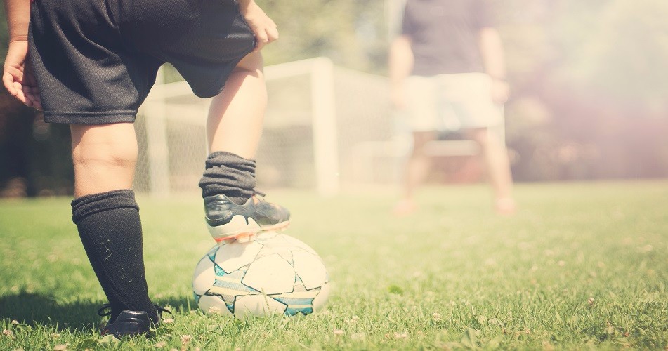 Close-up of football beneath child's foot