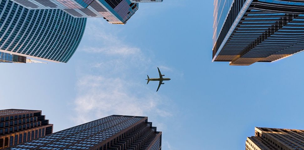 Picture of skyscrapers looking up toward a plane in the sky