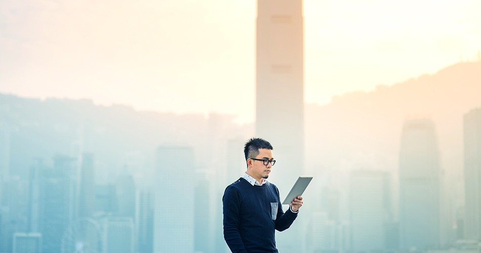 Picture of a man working on an electric tablet with city behind him