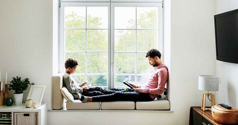 Picture of  father and son looking at electronic tablets by a window