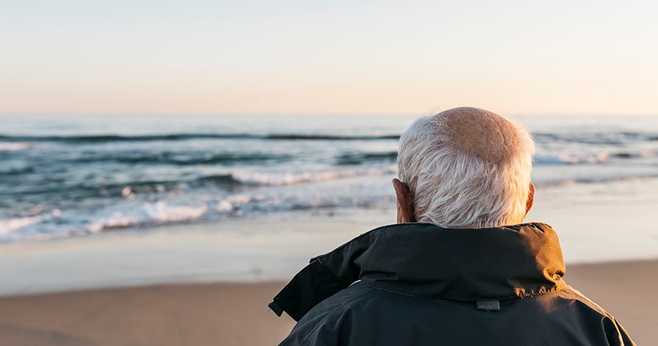 Picture of an elderly man looking onto the sea at the seaside