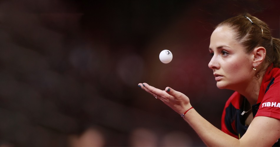 Picture of a woman throwing a ping pong ball in the air