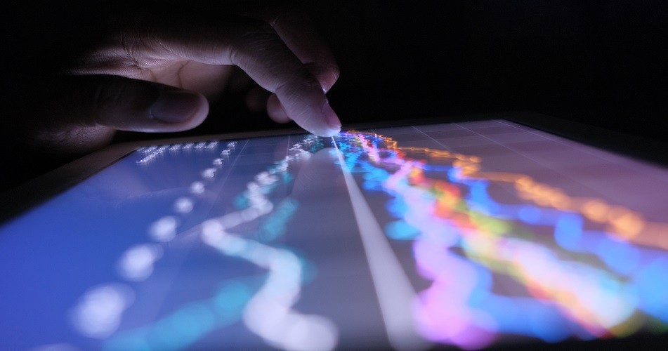 Picture of a hand touching a tablet screen with data on it