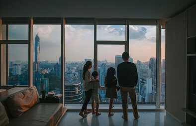 Family looking at Kuala Lumpur skyline through living room window
