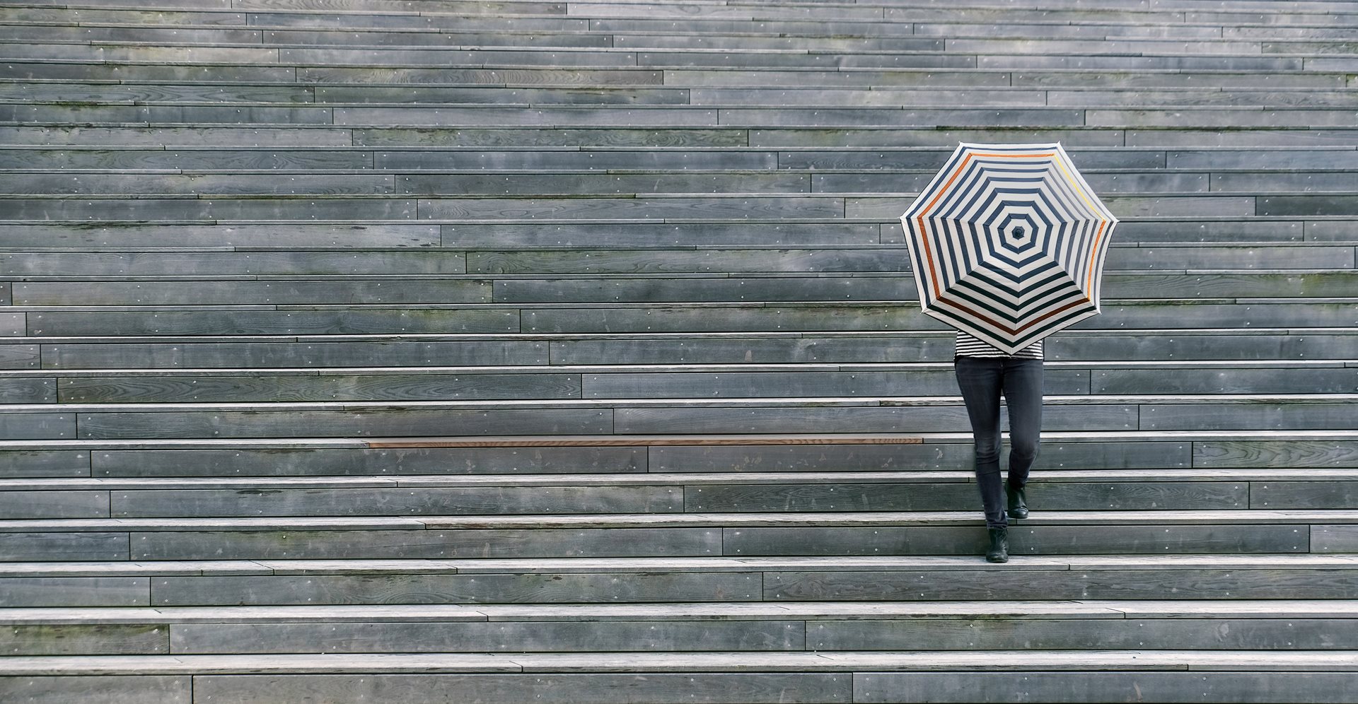 Woman standing behind umbrella on stairs