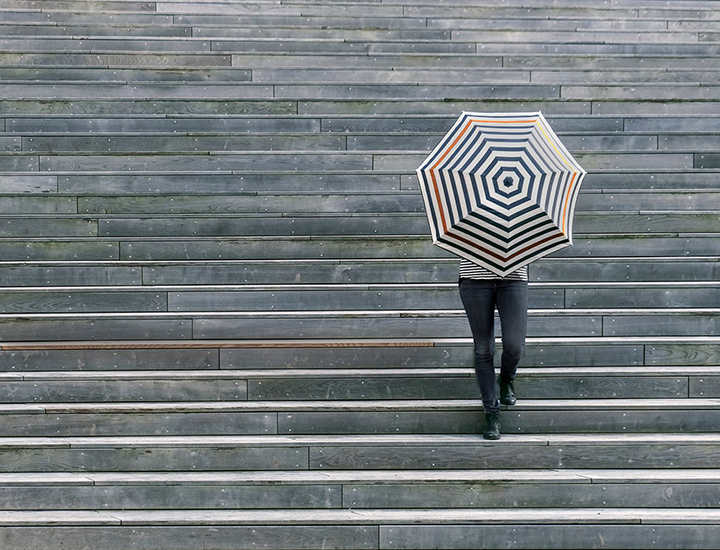 Woman walking down stairs behind closed umbrella