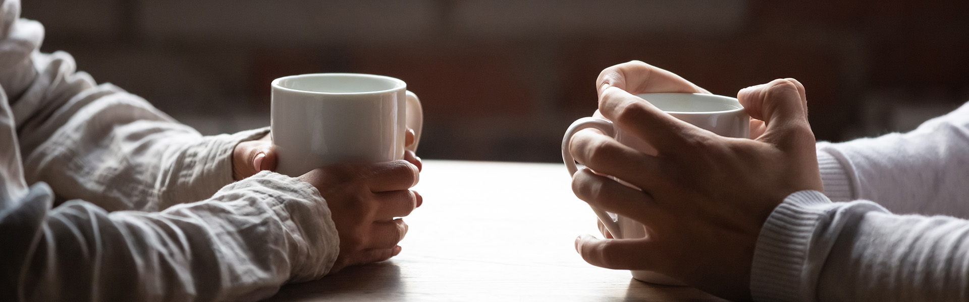 Close-up of couple holding cups of coffee on table