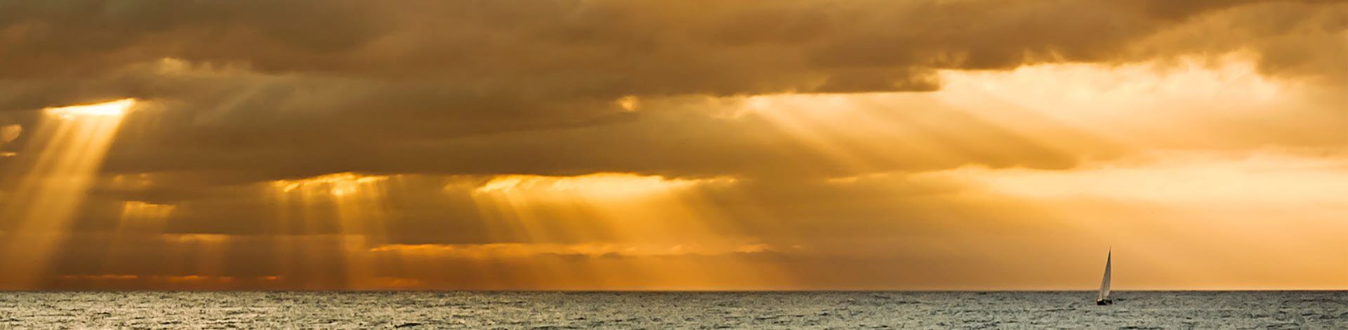 Sun rays shining through clouds onto the ocean