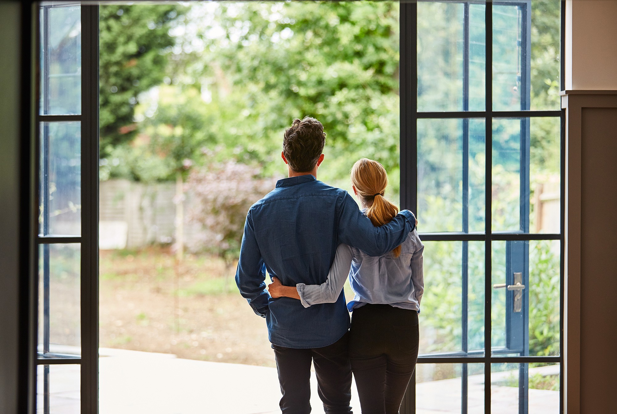 Couple with arms around each other looking out over garden