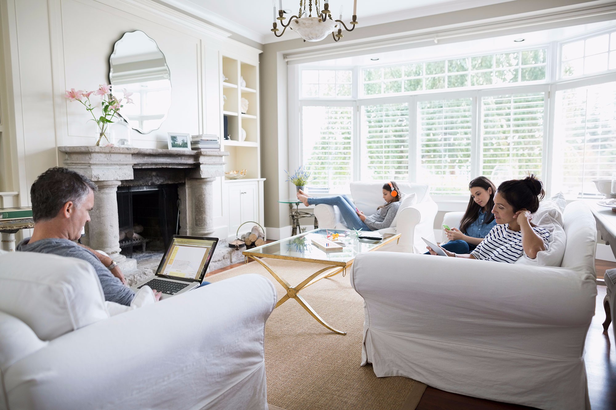 Family sitting in living room using mobile devices