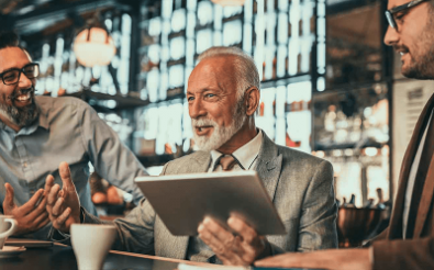 Three men sat talking with a tablet device