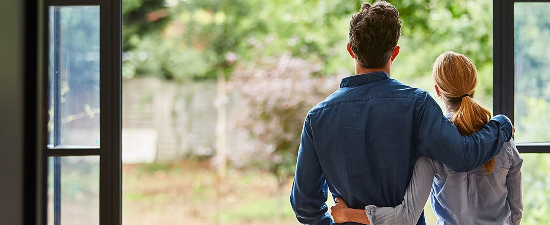 Couple standing at backdoors looking out over garden