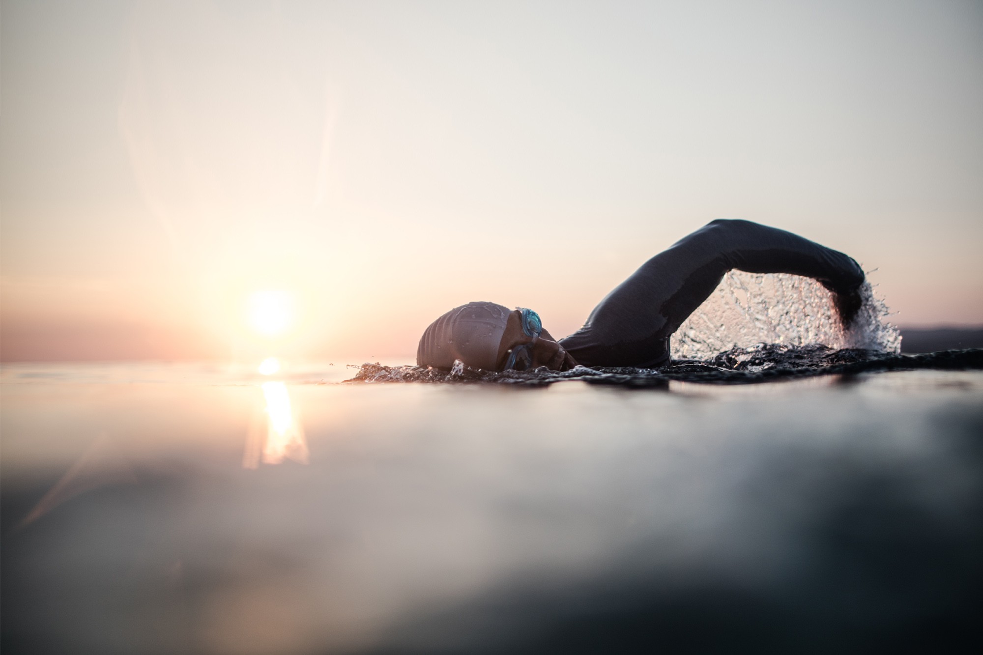 Person swimming at sunset