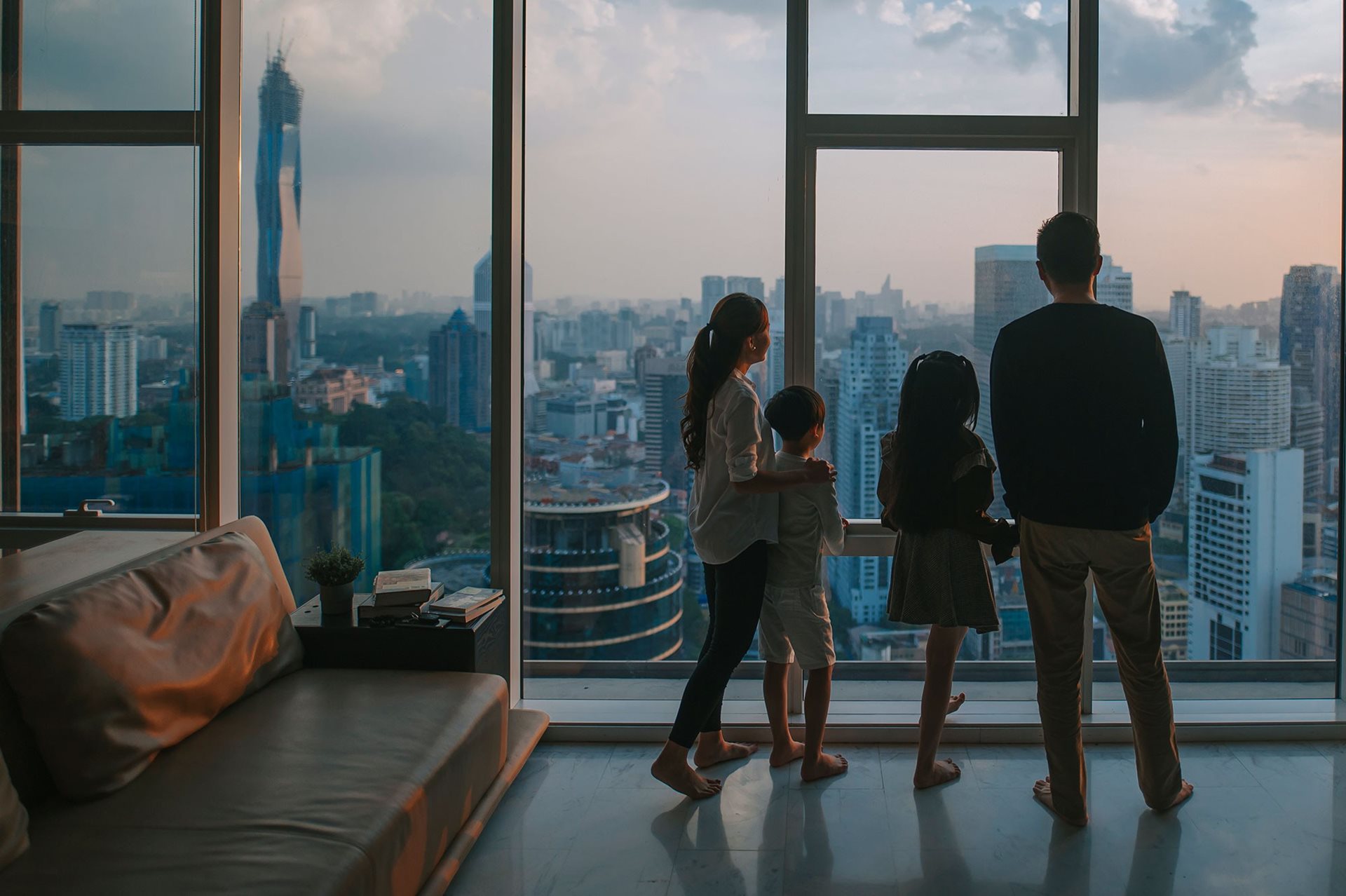 Family looking out at city from living room window