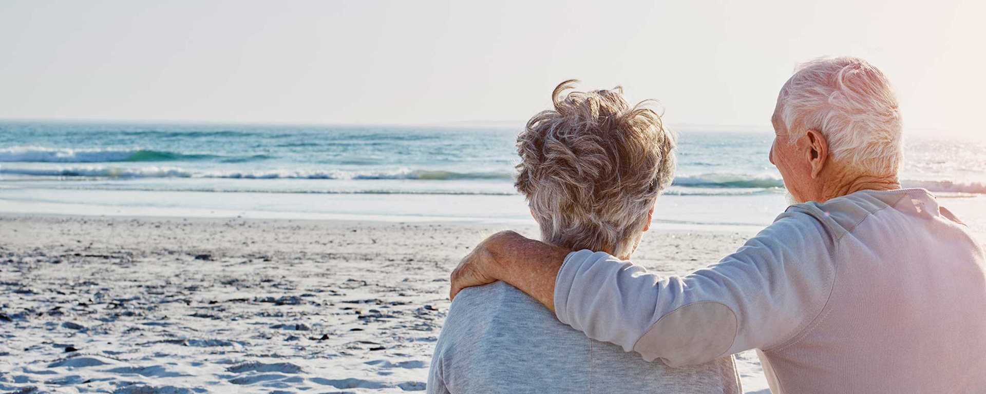 Old couple standing on beach looking towards the ocean