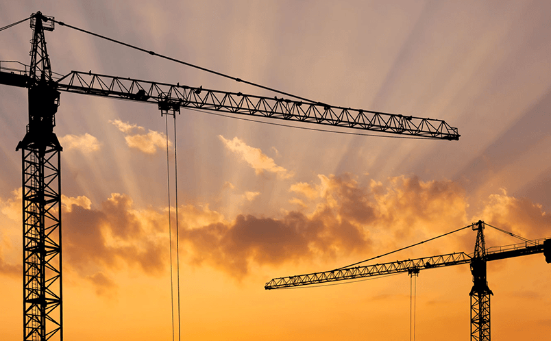 Construction cranes with sunset in the background
