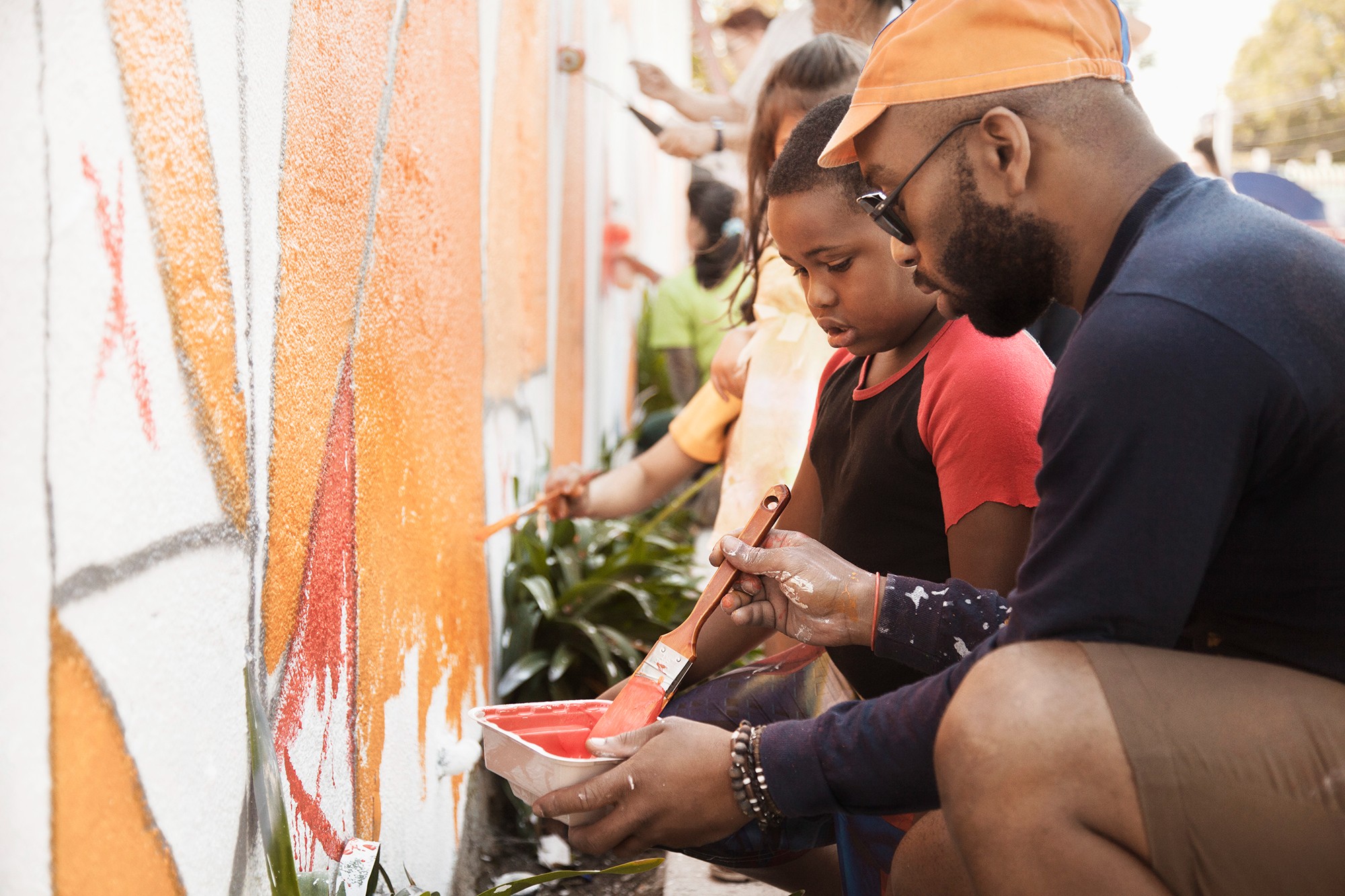 Parents helping children paint a wall