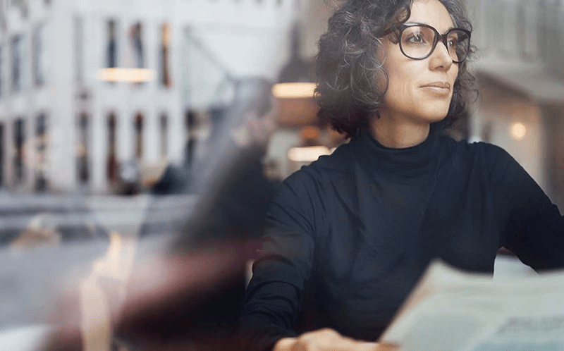 Woman looking out of window with newspaper