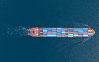 Boat with multicolored shipping containers floating through the ocean